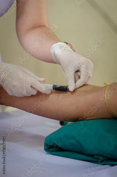 Obraz Soft focus on the hands of the doctor drawing a blood sample from the arm for blood test finds in hospital.