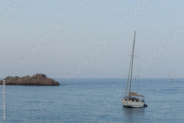 Fototapeta Yachting on a serene seascape at sea. A lone ship sailing on the water on a sunny summer day. Frontal view