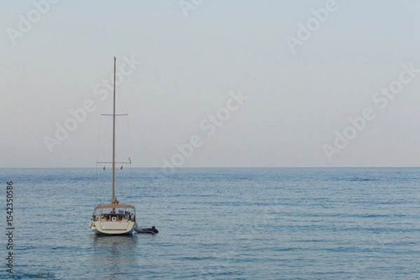 Fototapeta Yachting on a serene seascape at sea. A lone ship sailing on the water on a sunny summer day. Frontal view
