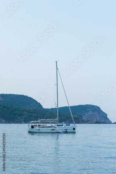 Fototapeta Yachting on a serene seascape at sea. A lone ship sailing on the water on a sunny summer day. Frontal view