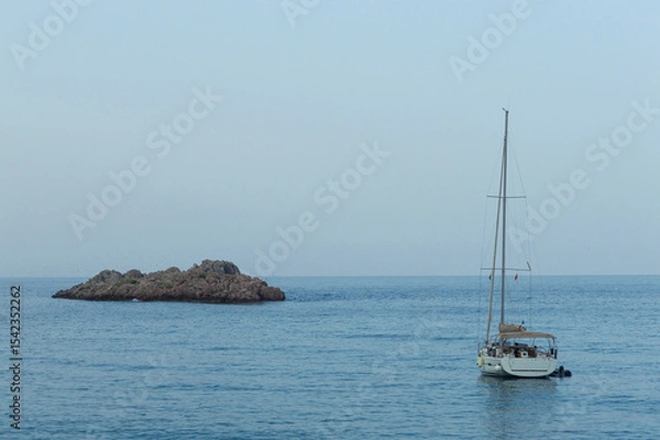 Fototapeta Yachting on a serene seascape at sea. A lone ship sailing on the water on a sunny summer day. Frontal view