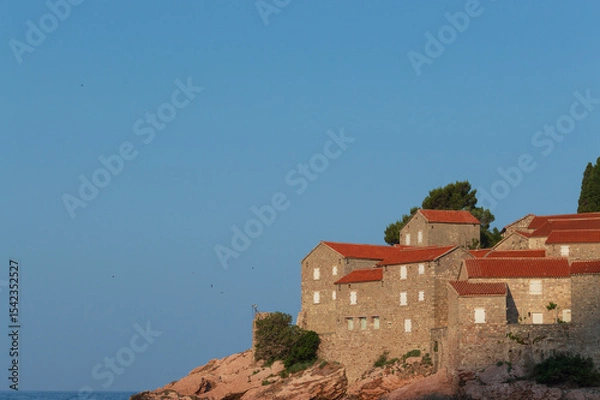 Fototapeta Sveti Stefan Island Hotel, stone houses of a medieval fortress village with tiled roofs on the Adriatic coast of Montenegro