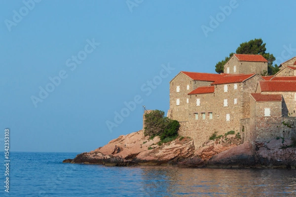 Fototapeta Sveti Stefan Island Hotel, stone houses of a medieval fortress village with tiled roofs on the Adriatic coast of Montenegro