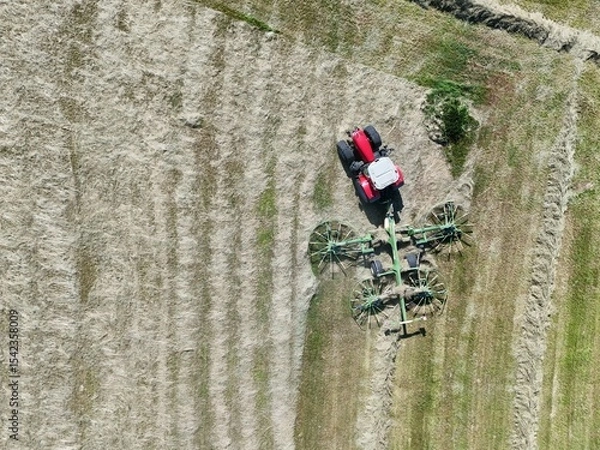 Fototapeta A tractor with a hay tedder in the field, shot with a drone