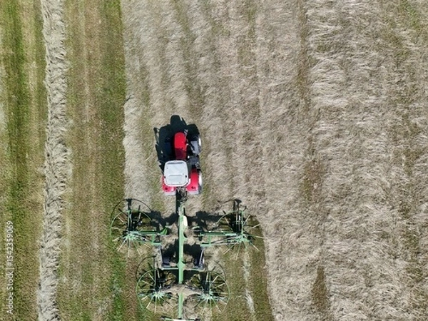Fototapeta A tractor with a hay tedder in the field, shot with a drone