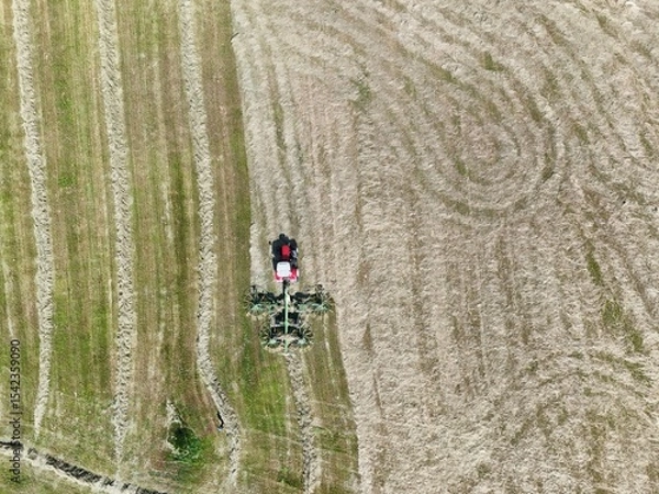 Fototapeta A tractor with a hay tedder in the field, shot with a drone