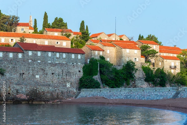 Fototapeta Sveti Stefan Island Hotel, stone houses of a medieval fortress village with tiled roofs on the Adriatic coast of Montenegro