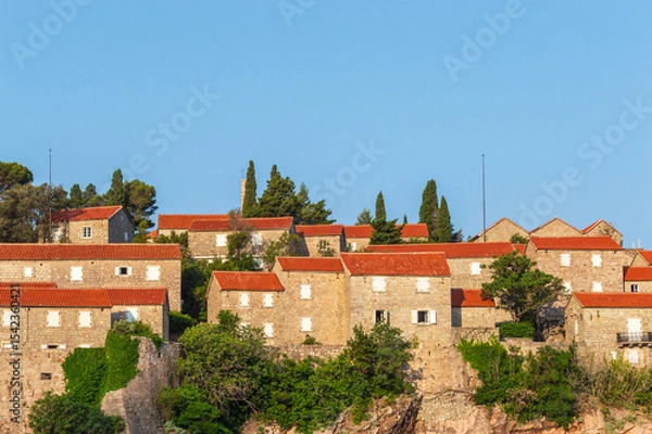 Fototapeta Sveti Stefan Island Hotel, stone houses of a medieval fortress village with tiled roofs on the Adriatic coast of Montenegro