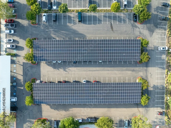 Fototapeta Aerial view of solar panels installed as shade roof over parking lot for parked cars. Photovoltaic technology integrated in urban infrastructure. High quality photo
