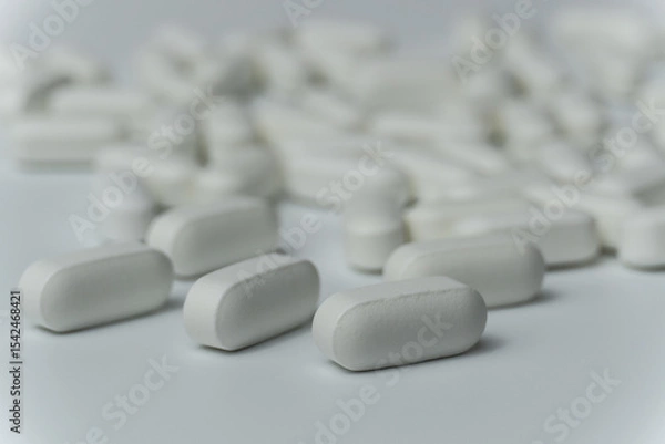 Fototapeta Group of white pills tablets on a light grey background close up macro
