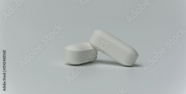 Fototapeta Close up macro shot of a two tablets pills on a light grey background