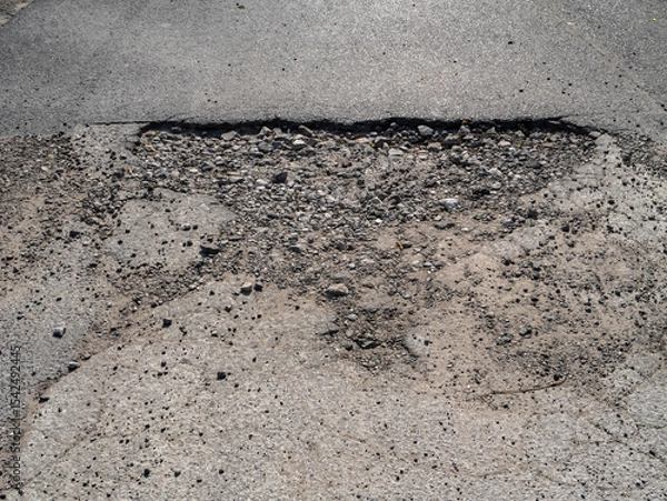 Obraz Large pothole in damaged asphalt road, hazard for vehicles and indicator of poor infrastructure maintenance