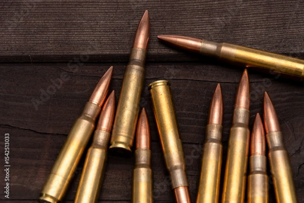 Obraz Close-up of various calibres of ammunition lying on a rough wooden board. Suitable for topics related to hunting, shooting or military affairs.