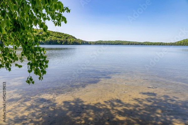 Fototapeta A serene view of the calming waters of Solitaire Lake surrounded by lush greenery in Huntsville, Muskoka, Ontario.
