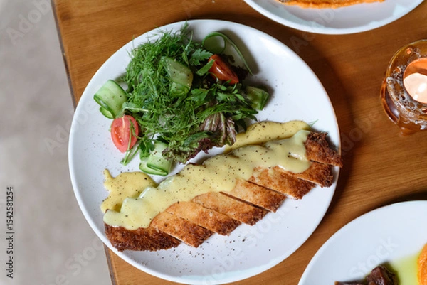 Obraz Tender meat served with creamy mashed potatoes and fresh salad on a plate for a satisfying hotel dining experience