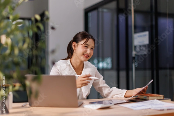 Obraz Young business Asian woman working on a laptop computer in a office,doing finances, accounting analysis, report data pointing graph Freelance education and technology concept.
