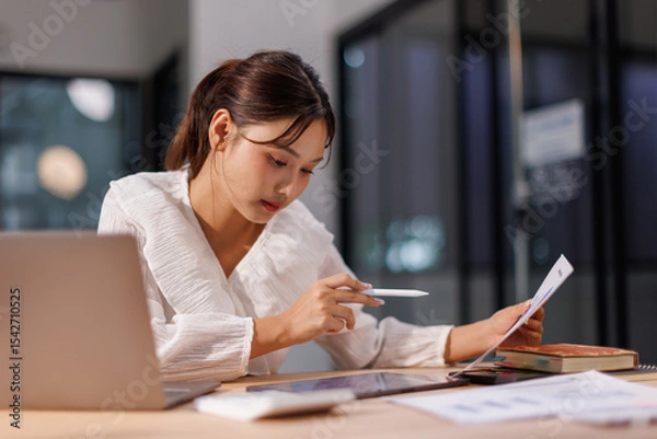 Obraz Young business Asian woman working on a laptop computer in a office,doing finances, accounting analysis, report data pointing graph Freelance education and technology concept.
