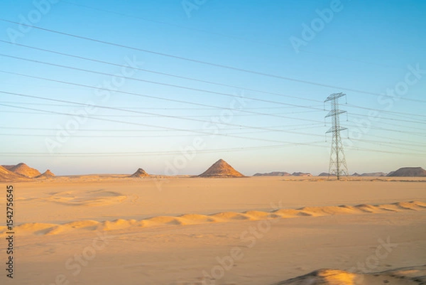Obraz A stunning view of power lines crossing the desert landscape at sunrise in Aswan, Egypt, showcasing the beauty of the arid terrain and the infrastructure.