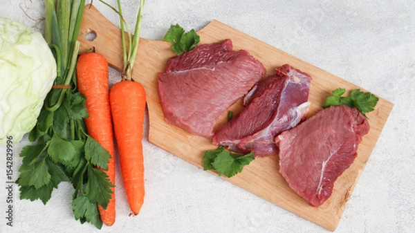 Obraz fresh raw meat on a cutting board with soup vegetables on the side