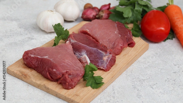 Obraz fresh raw meat on a cutting board with soup vegetables on the side