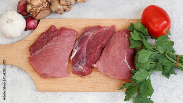 Obraz fresh raw meat on a cutting board with soup vegetables on the side. top view. flatlay