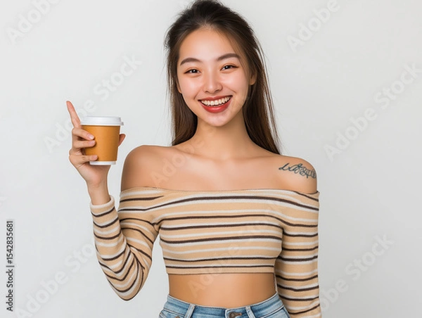Fototapeta Happy Young Woman in Striped Top Presenting Coffee Cup – Studio Portrait with White Background for Advertising, Branding, or Promotional Use