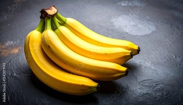 Fototapeta A Bunch of Ripe Yellow Bananas on a Dark Surface