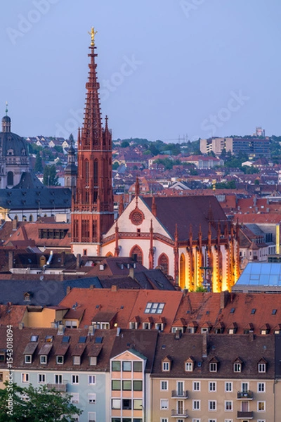 Fototapeta Wurzburg's Marian Chapel illuminated at dusk with city rooftops in the foreground - Germany