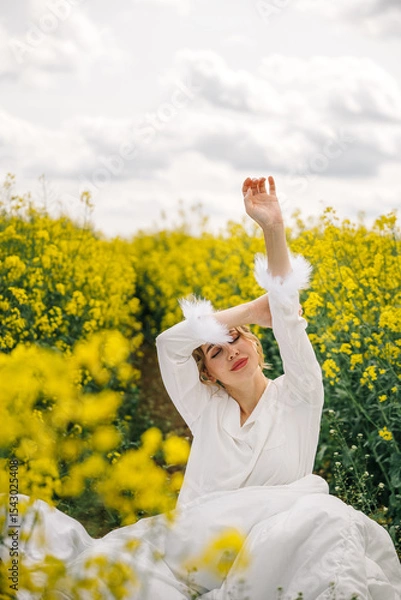 Fototapeta Woman enjoying a sunny day in a field of bright yellow flowers during springtime