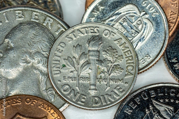 Fototapeta One dime US Dollar on top of different currency coins on white background macro
