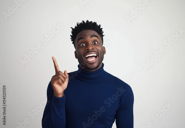 Fototapeta Excited Man in Blue Turtleneck Pointing Up – Portrait with Happy Expression, White Background, Ample Space for Text, High-Resolution Studio Photography for Advertising & Social Media Concepts