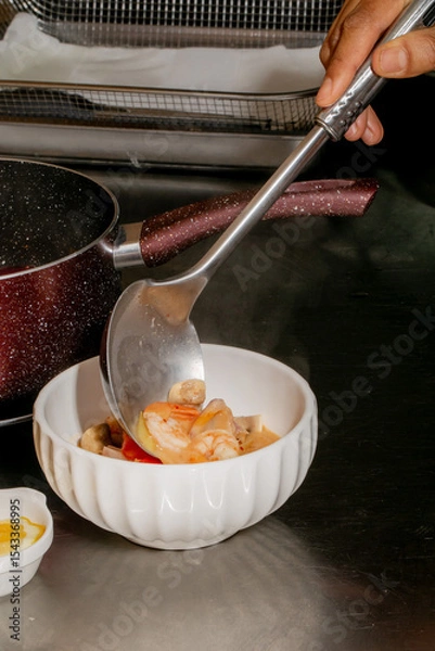 Fototapeta A hand serves steaming shrimp bisque into a fluted porcelain bowl, echoing Lunar New Year prosperity and coastal tranquility