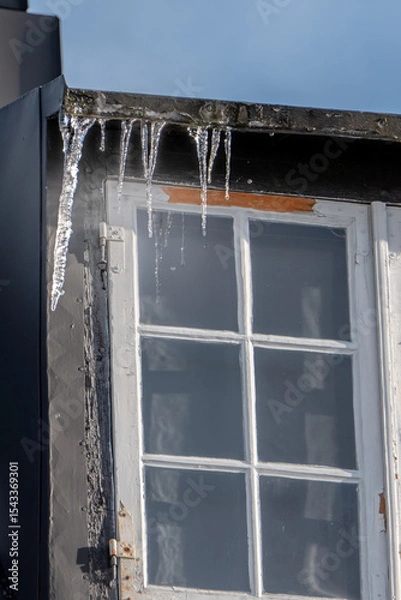 Fototapeta Close-Up of Icicles Hanging from an Old Wooden Window Frame in Winter Sunlight