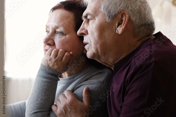 Fototapeta Senior couple using laptop together in the room. Embracing elderly man and woman reading email or online shopping choice. Old man and woman talk at table in home together on internet, social media. 4K