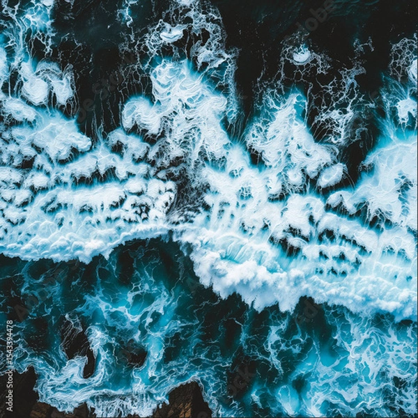 Fototapeta Aerial view of crashing ocean waves and swirling white foam over dark water