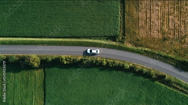 Obraz car driving on the road near empty green fields, view straight from the top
