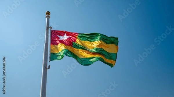 Fototapeta Realistic depiction of the flag of Togo waving in a clear blue sky during daytime hours