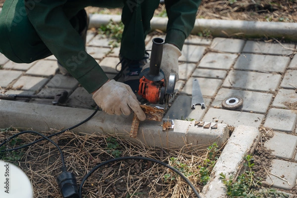 Fototapeta A man cuts off a piece of metal with a grinder. The grinder is in the hands of a master. Construction works.