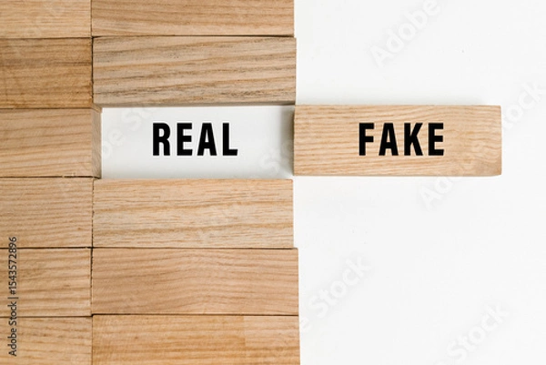 Fototapeta real and fake words text on wooden blocks isolated on white background