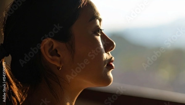 Fototapeta Quiet Contemplation: A moment of introspective stillness, a woman's profile, bathed in soft, warm light, gazes out at a scenic vista. Capturing the quiet peace of a reflective moment.