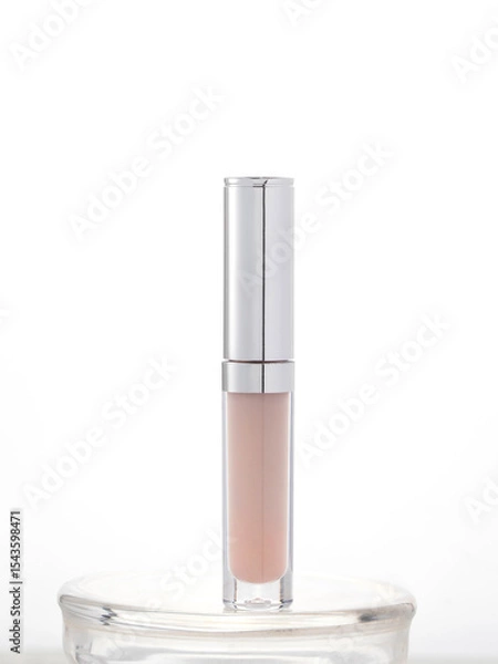 Fototapeta Sleek transparent cosmetic container with metallic cap, ideal for lip gloss, concealer, or serum. Clean, professional presentation for beauty product advertising or branding.