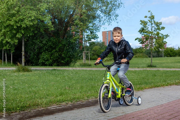 Obraz A little boy rides a bicycle in the park during the summer