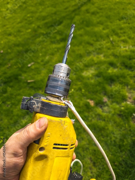 Obraz Damaged drill with electrical cord in grassy yard