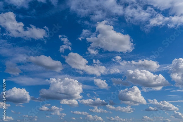 Fototapeta Delicate fluffy cumulus clouds drift across a serene blue sky, creating a peaceful and airy atmosphere in this minimal natural landscape.