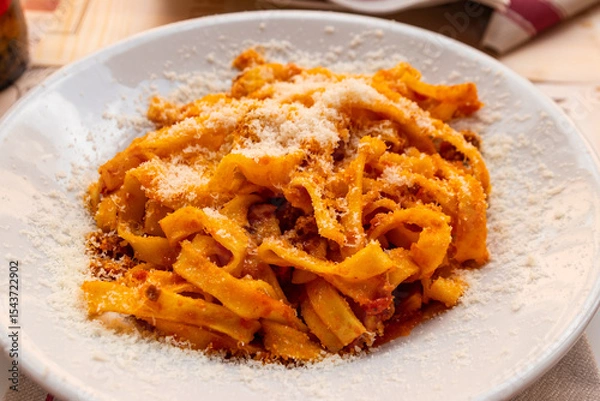 Obraz Tagliatelle pasta with bolognese sauce and grated cheese on a table