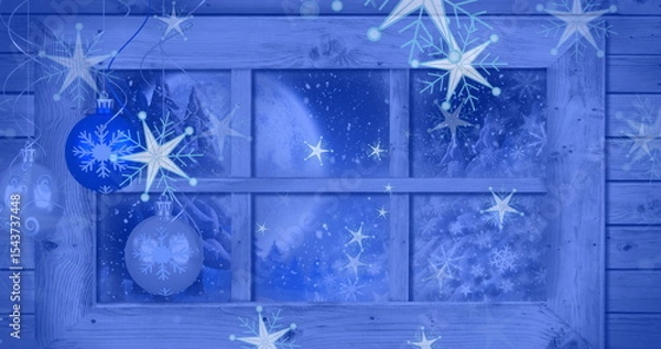 Fototapeta Displaying window with frost in cabin, hanging blue snowflake baubles before moonlit pine forest
