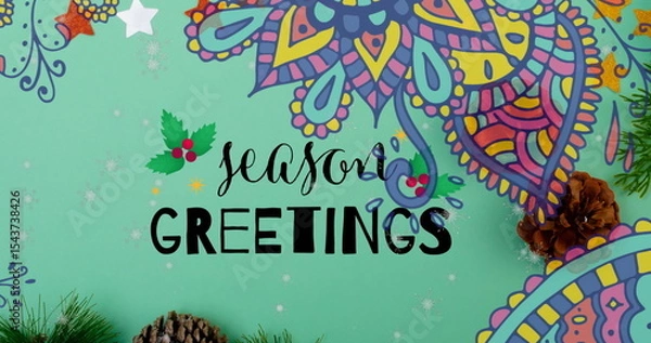 Fototapeta Displaying Season's Greetings lettering on mint-green background, with holly icon and pine cones