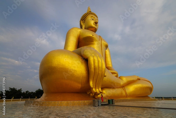Obraz The largest golden Buddha statue with green rice field foreground at Wat Muang Temple in Ang Thong Province, Thailand.