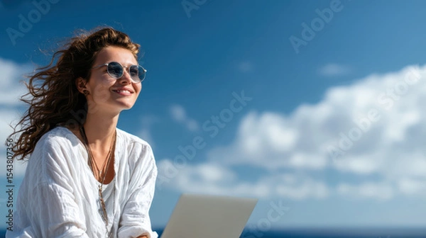 Fototapeta Young Woman Sitting on Rooftop with Laptop Enjoying Sunny Day Amidst Clear Blue Sky and Calm Ocean Breeze