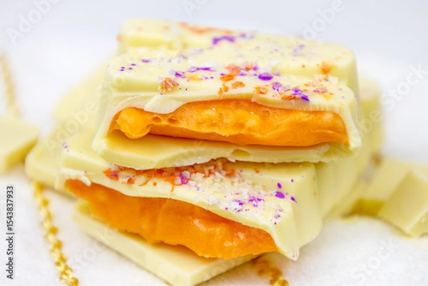 Fototapeta White Mango Dubai Chocolate bar with orange mango, passion fruit spread filling with popping candy close up